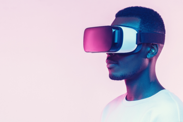 Head and shoulders of a Black man wearing a white t-shirt and a white virtual reality headset