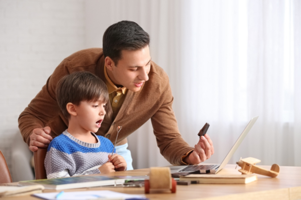 A speech therapist holding up a wooden letter 'A' in front of a young boy.